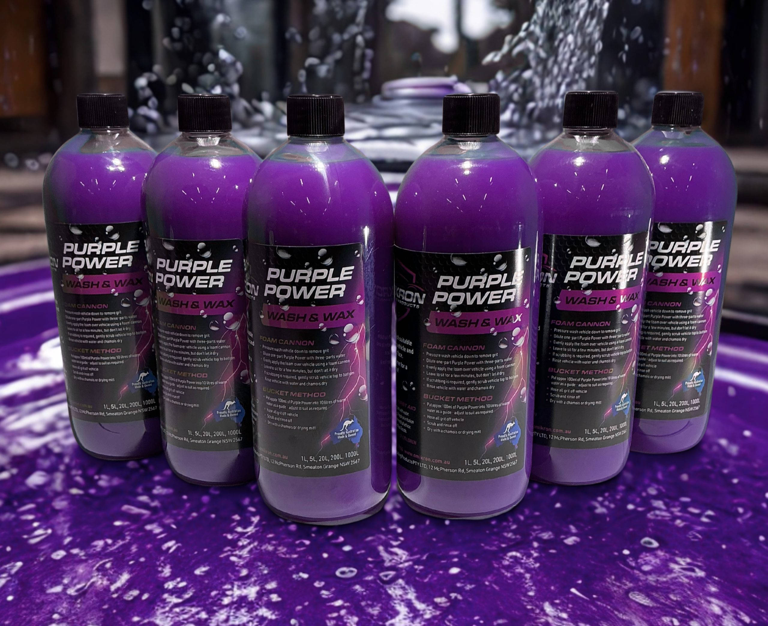 Line of Omikron Purple Power Wash & Wax 1L bottles displayed on a foamy purple surface